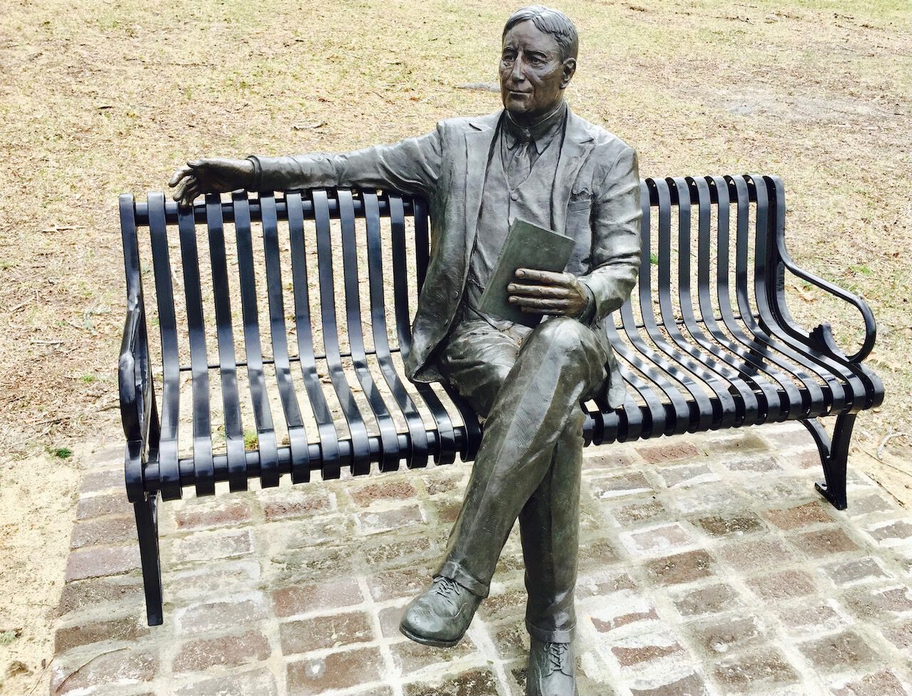 statue of man sitting on a park bench